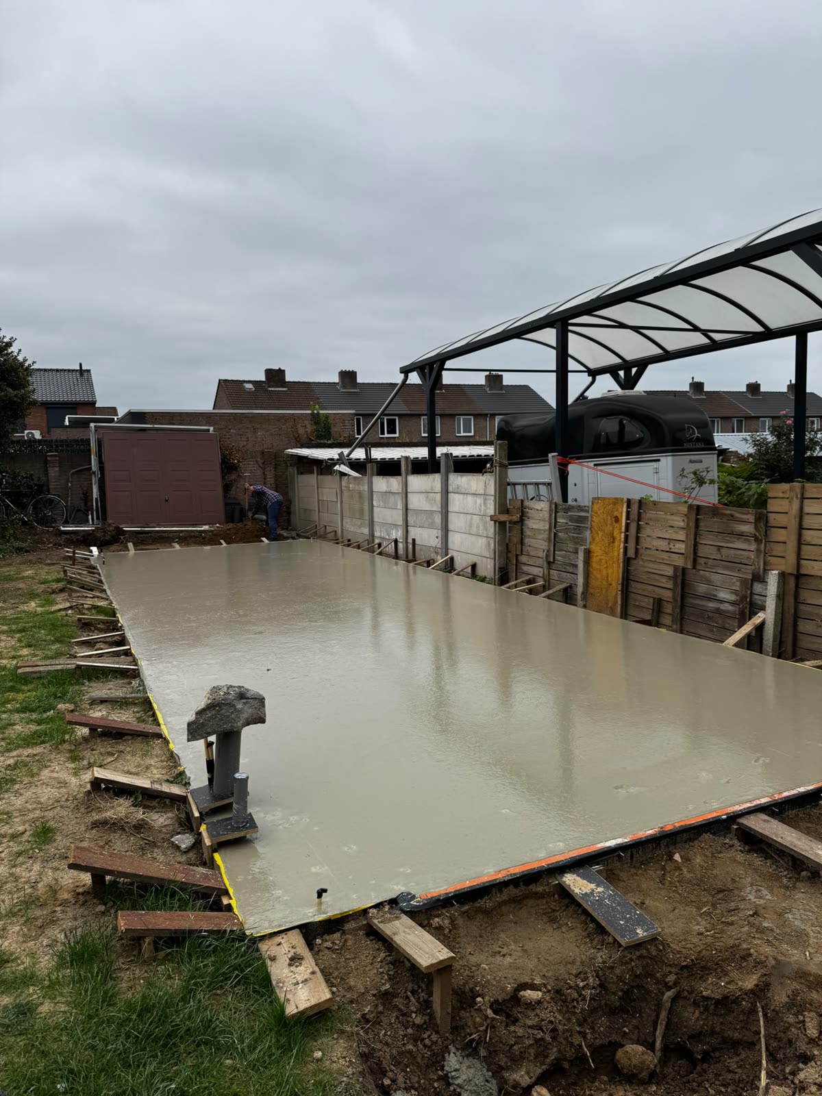 Betonvloer gestort in de achtertuin onder een pergola
